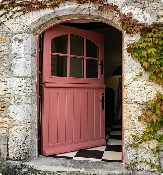 Porte extérieure en bois rose dans une façade en pierre